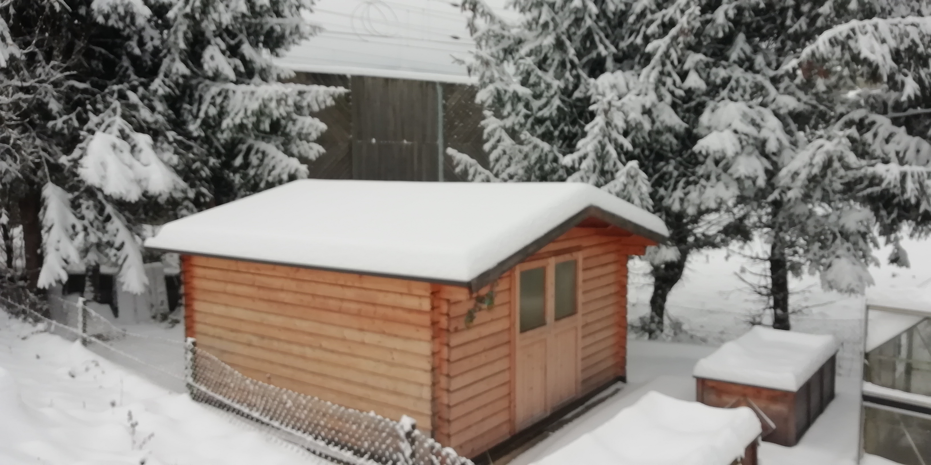 ein Foto von einer Holzhütte, die mit Schnee bedeckt ist